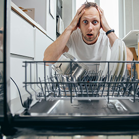 mann steht verzweifelt vor kaputtem geschirrspueler