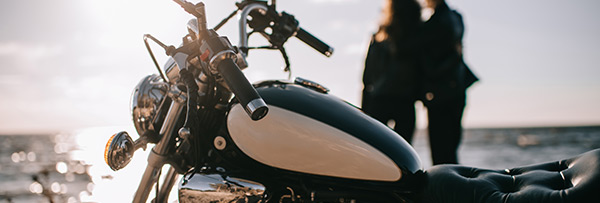 motorradfahrer mit motorrad beim sonnenuntergang am meer