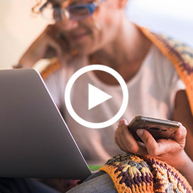 frau vor laptop mit smartphone in der hand