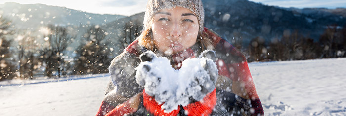 frau blaest schnee vom handschuh