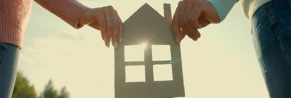 zwei h&auml;nde halten ein haus aus papier