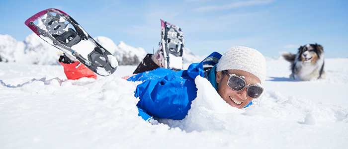 mann mit schneeschuhen und einem hund hat freude im schnee