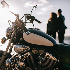 motorradfahrer mit motorrad beim sonnenuntergang am meer
