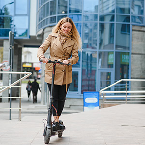 frau fährt mit dem e-scooter zur arbeit