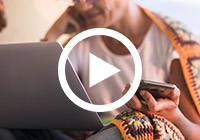 frau vor laptop mit smartphone in der hand